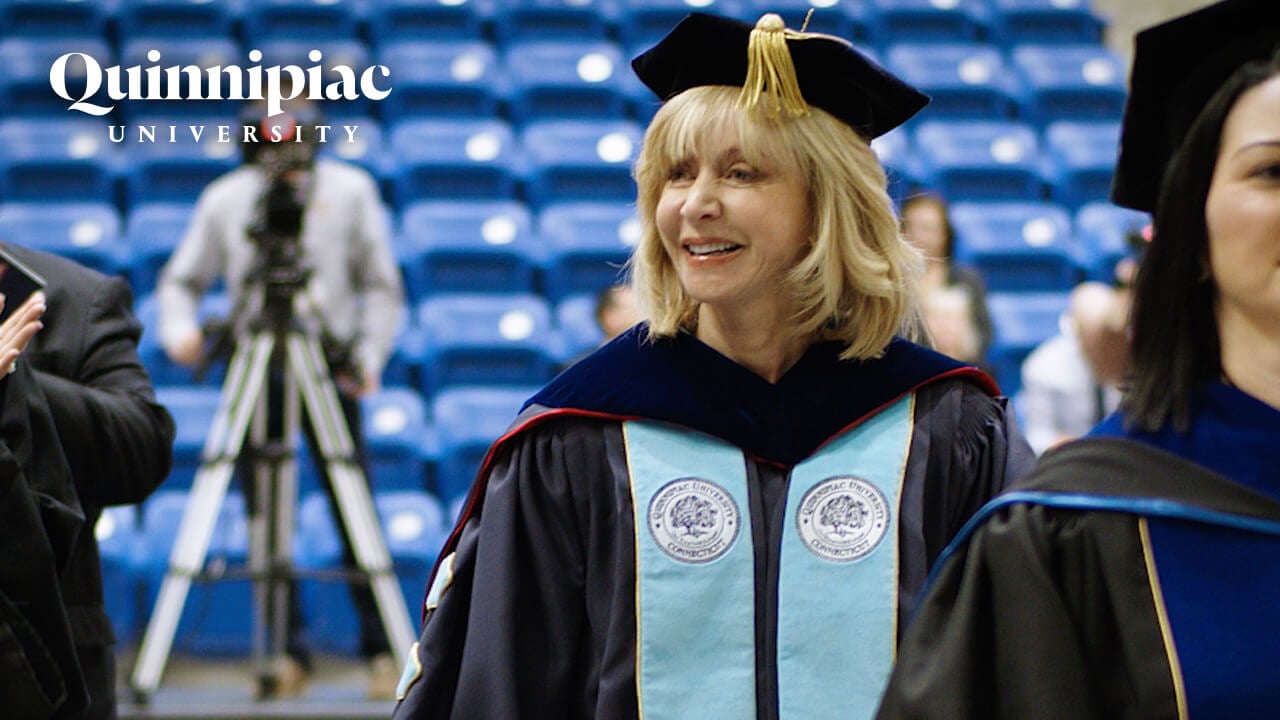 President Judy Olian in academic regalia, plays video