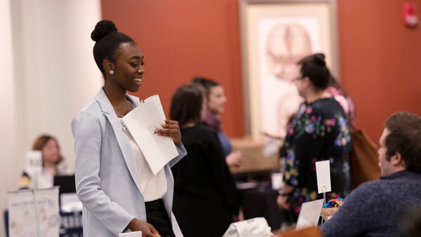 A female student holding a folder speaks to someone off camera