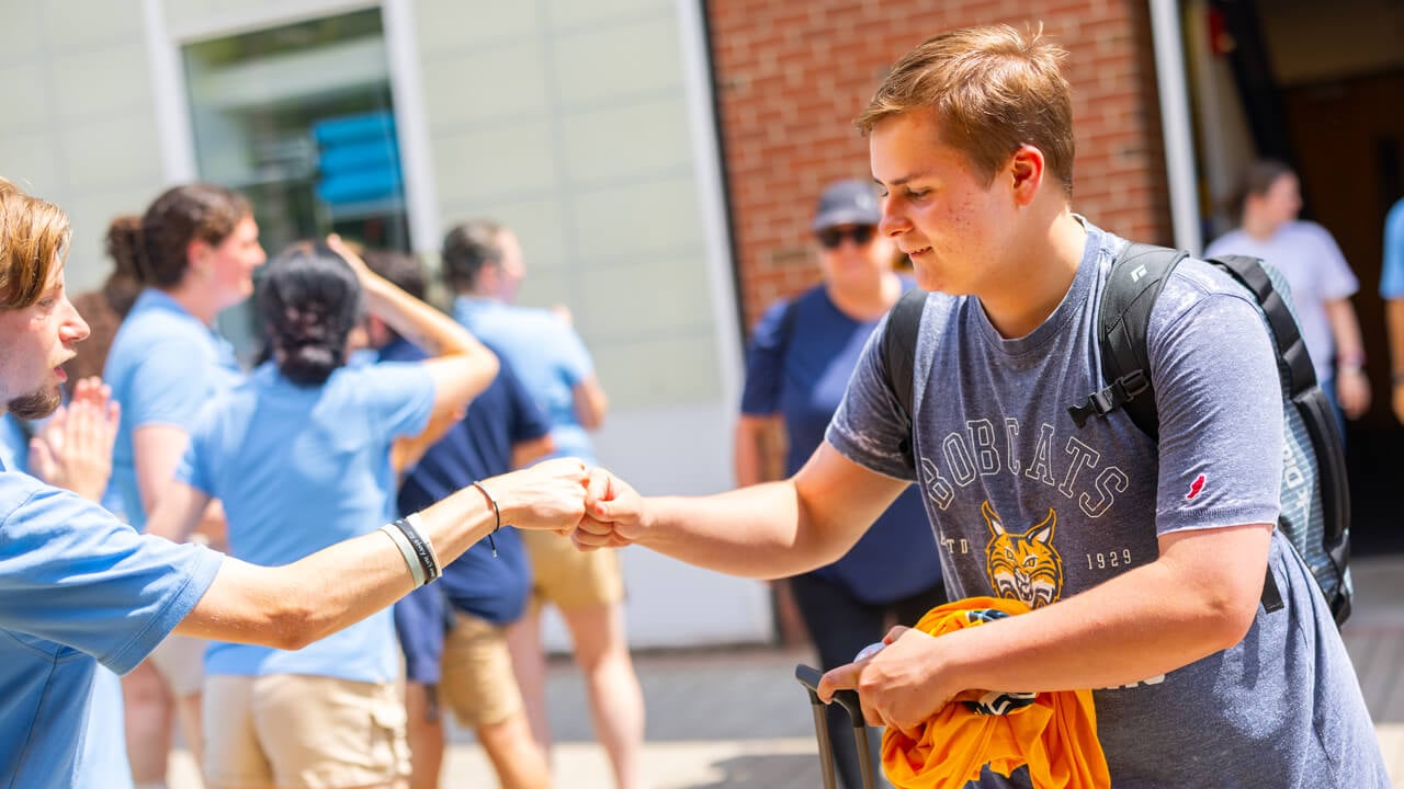 Two individuals fist bumping at Orientation