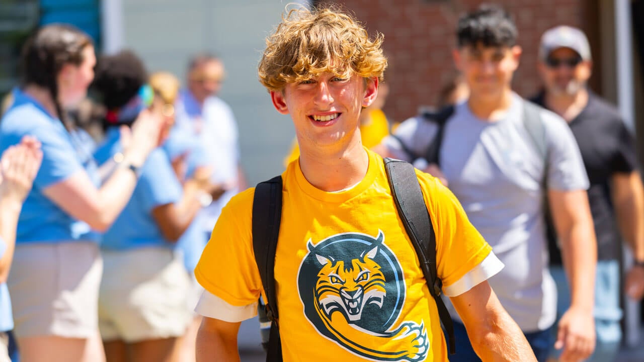 Individual smiles while walking and carrying a backpack.