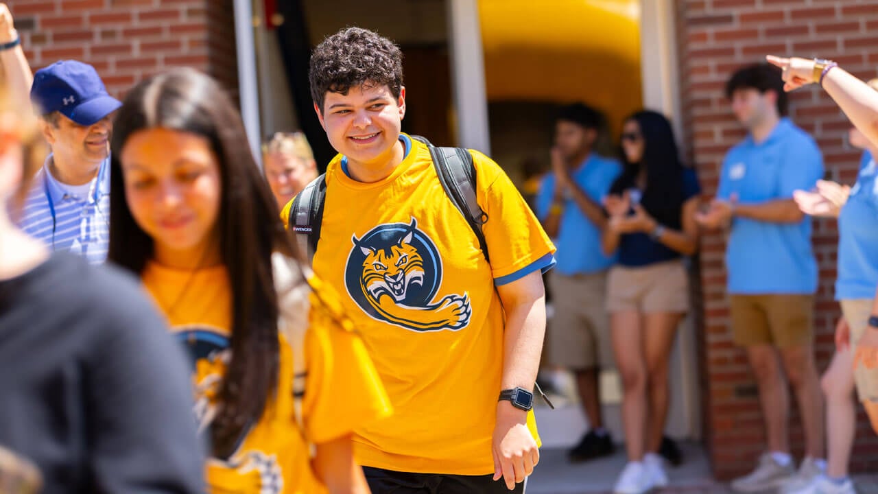 Individual smiles while walking and carrying luggage.