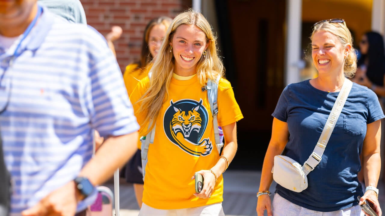 Individual carries suitcase and smiles with loved ones.
