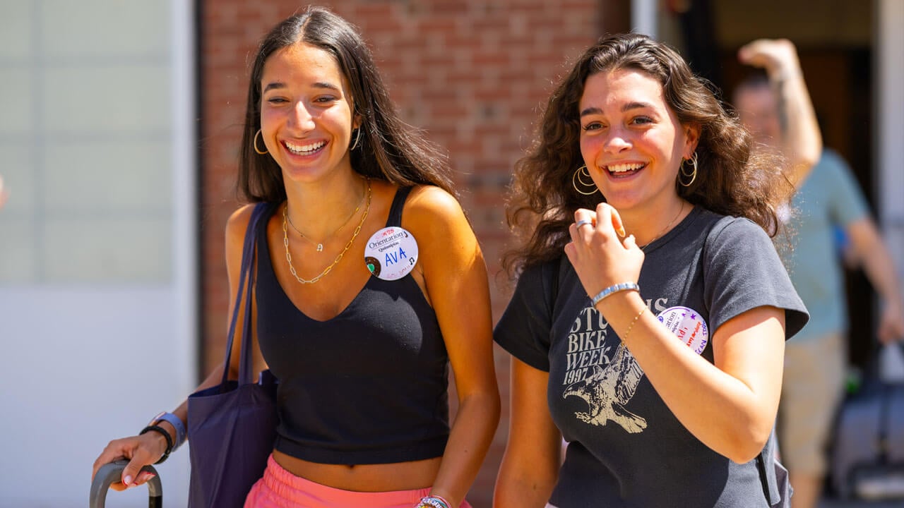 Two individuals smile while walking together.