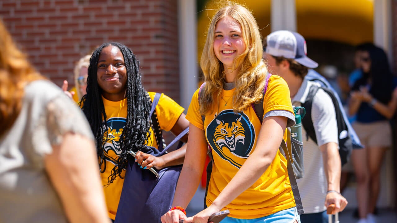 Individual walks with luggage and suitcase out of the Recreation and Wellness Center.