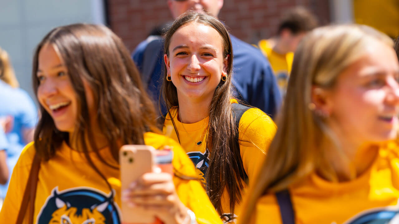 Individual smiles at the camera while walking through the crowd.