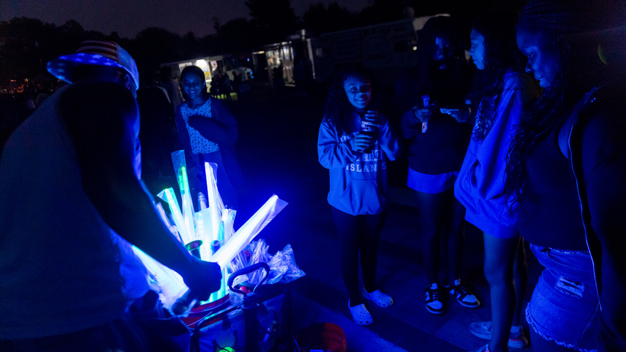 Families faces glow as they buy light up merchandise in the dark