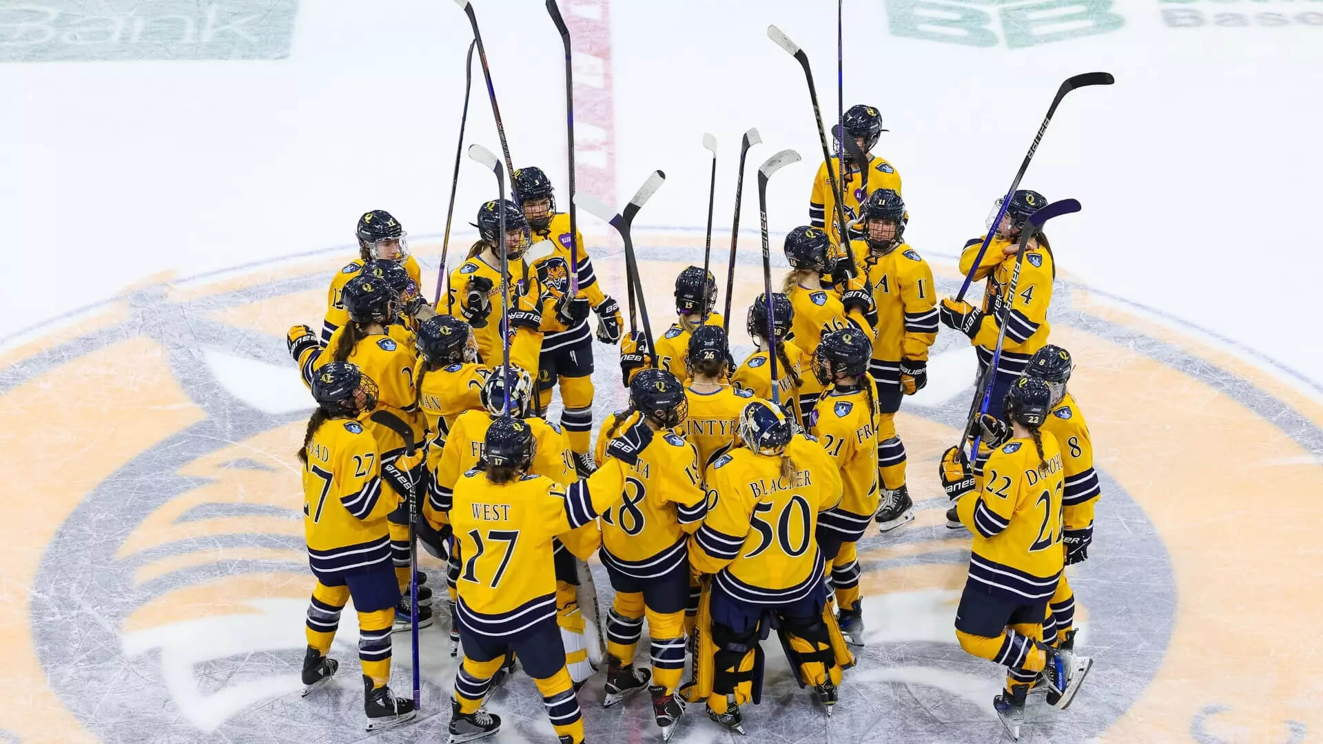 Ice hockey players stand in a circle on the ice.