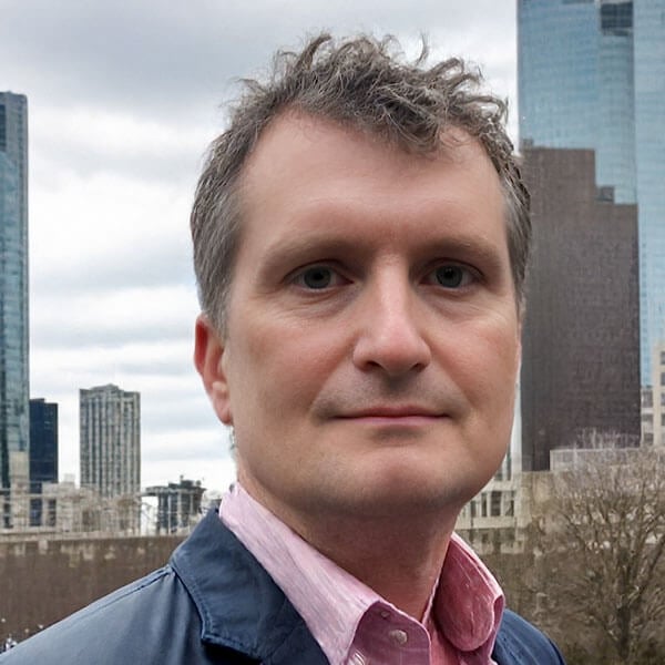 Scott Devito smirks against a city skyline