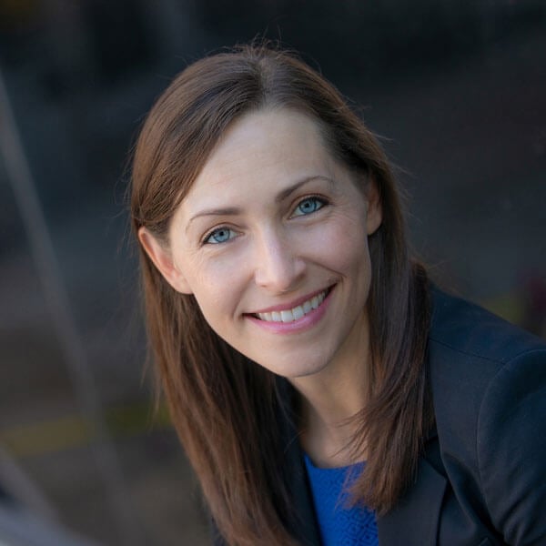 Larisa Bowman smiles in a blue shirt against a blurred background