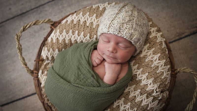 Murphy baby is wrapped up and wears a cozy hat while he sleeps