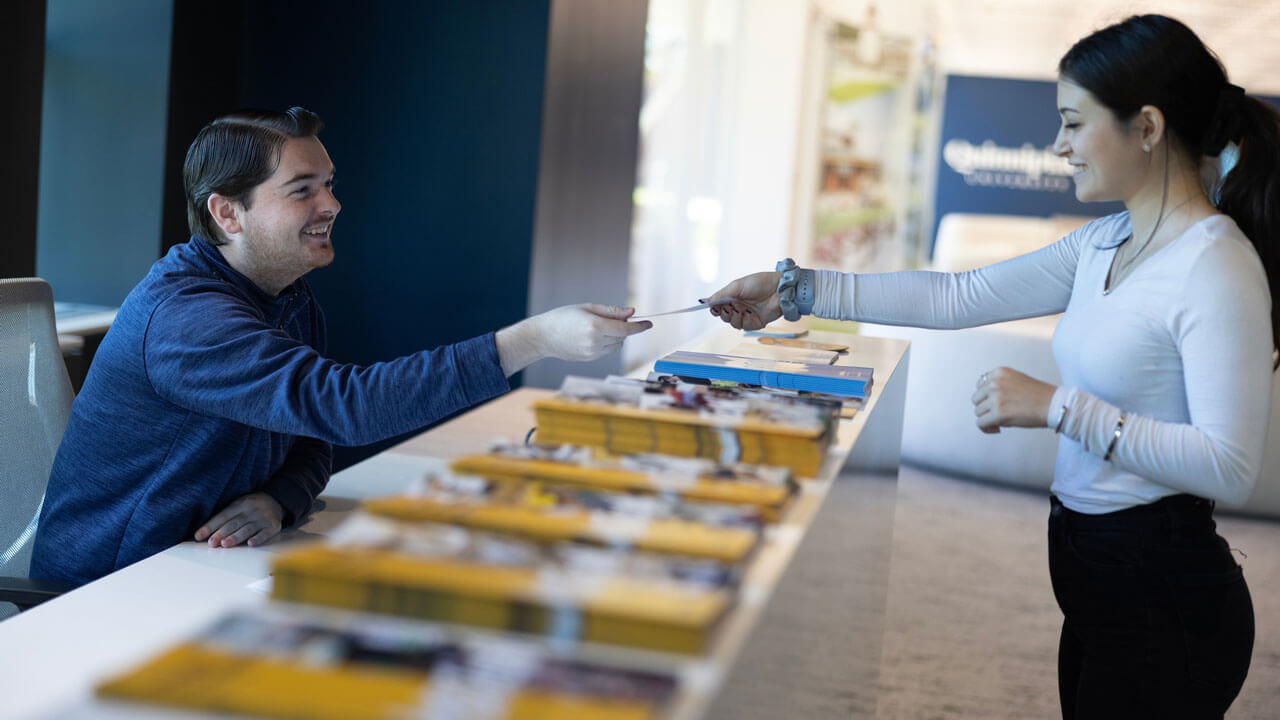 Student worker handing pamphlet to another student