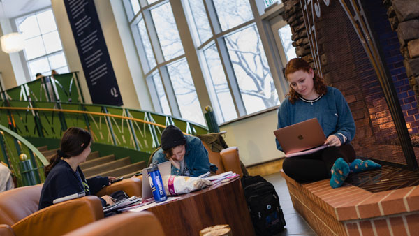 Students sitting next to the fireplace in the Piazza