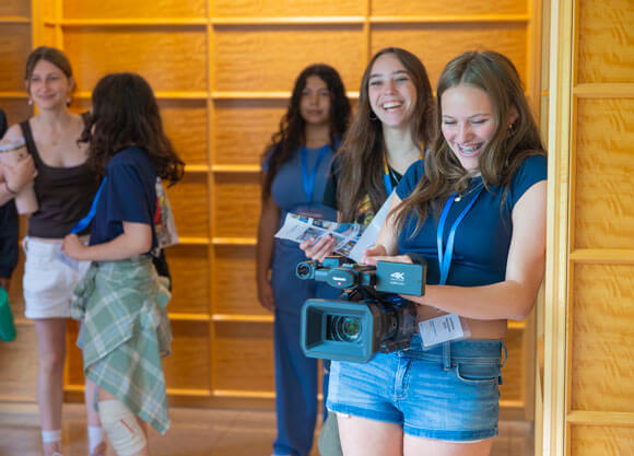 Camper joyfully holds a video camera ready to film