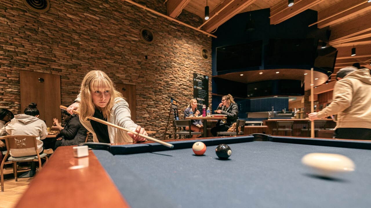 A student hits the cue ball in the pub