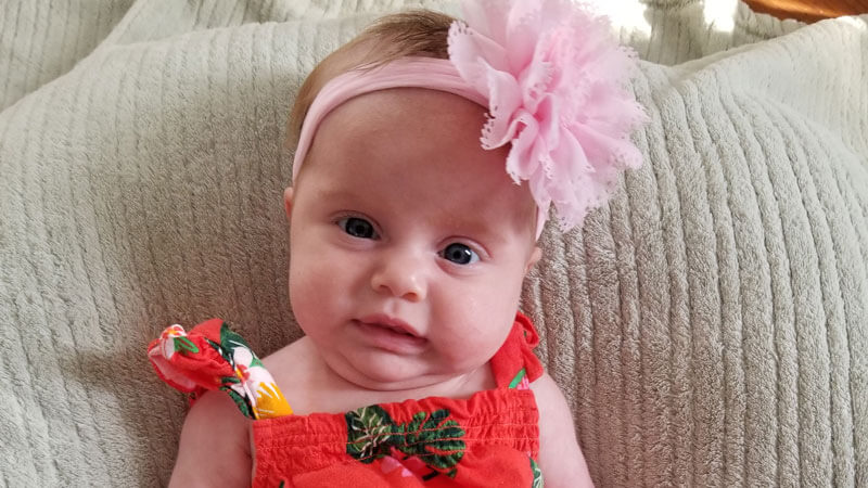 Summer Kuchyt wears a large flower headband and smiles on the couch