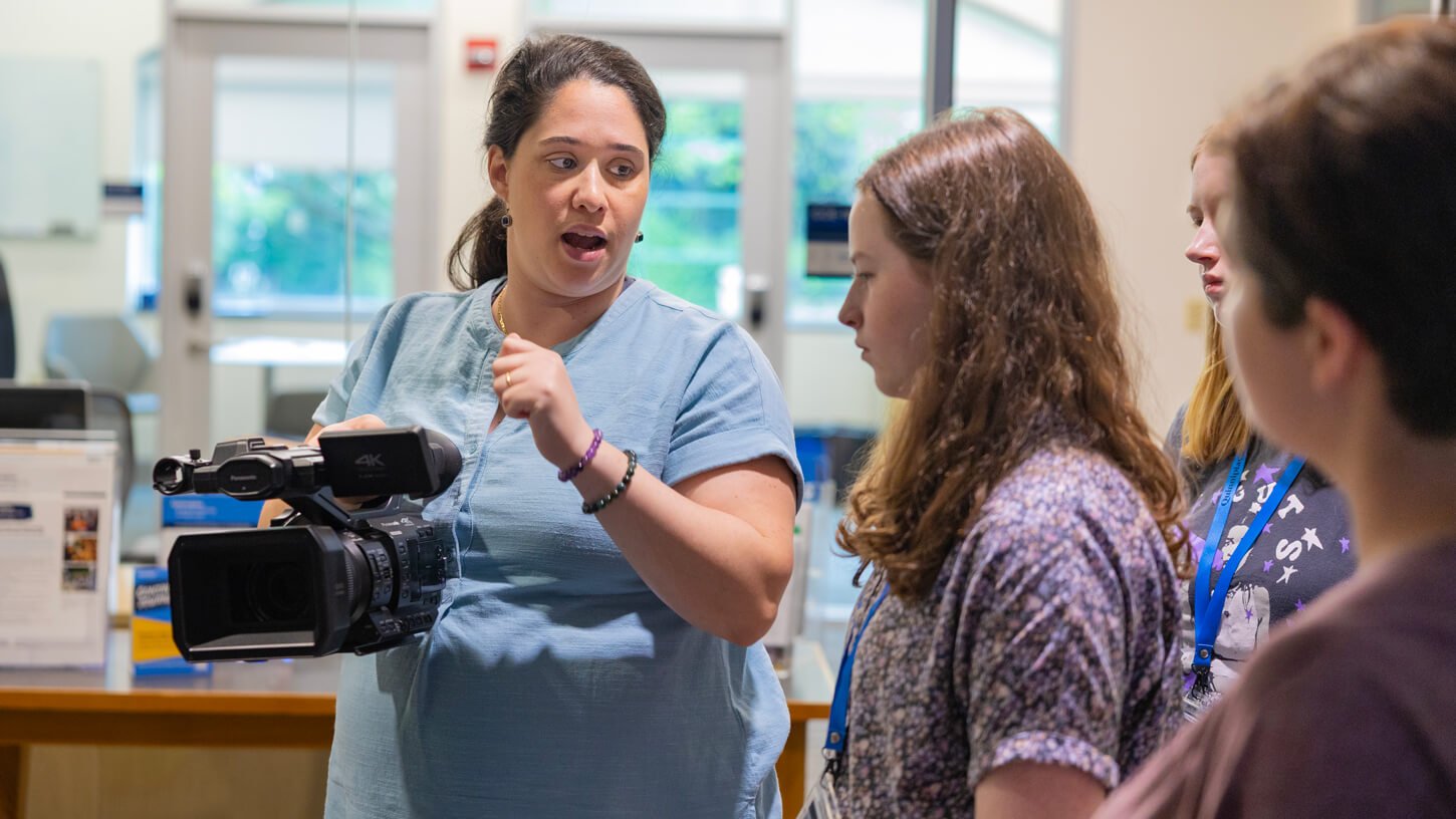Instructor explaining video camera functions to a small group of high school students during Quinnipiac University’s Movie Making Summer Camp.