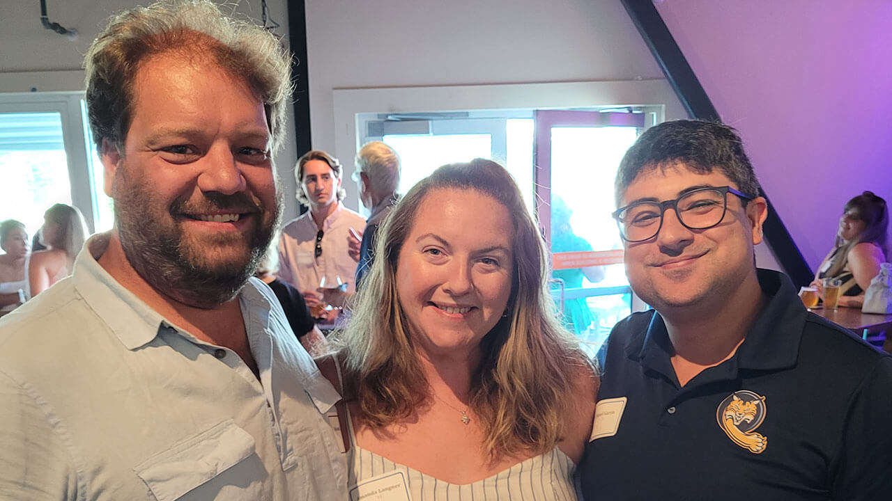 Three alumni take a photo together at an alumni event