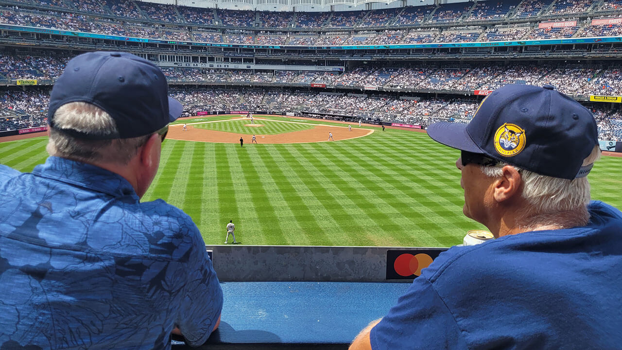 Two alumni watch the Yankee game closely