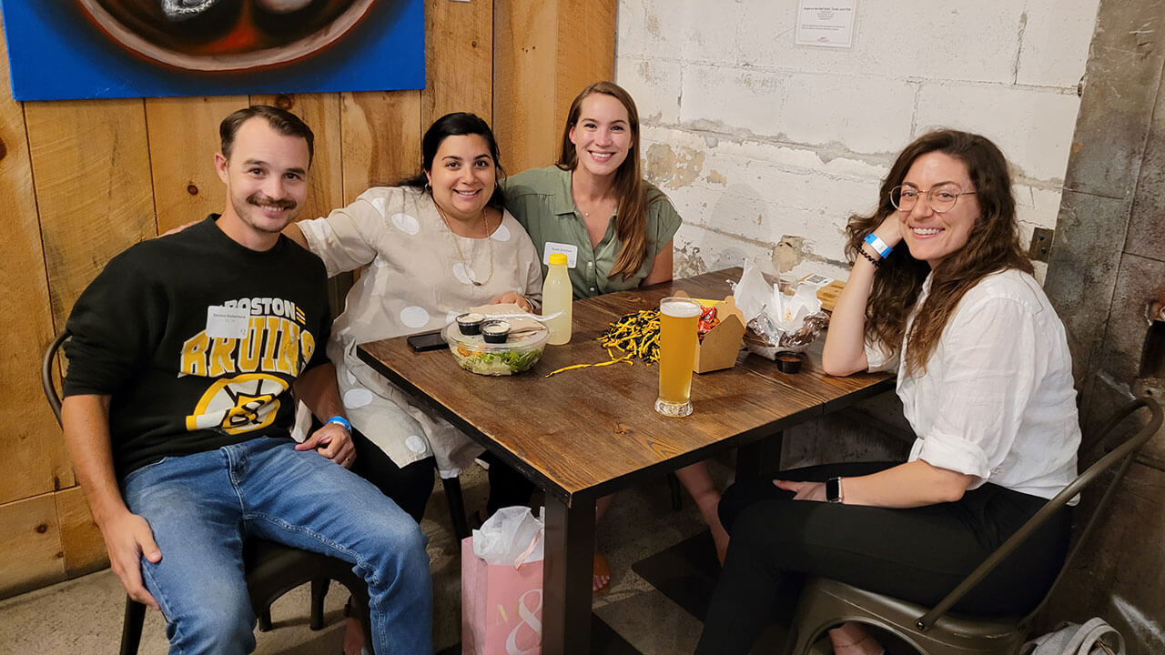 Alumni sit at a table and converse over a meal