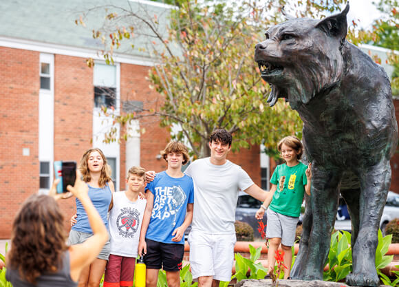 A parent takes a photo of a student and their siblings in front of the Bobcat statue