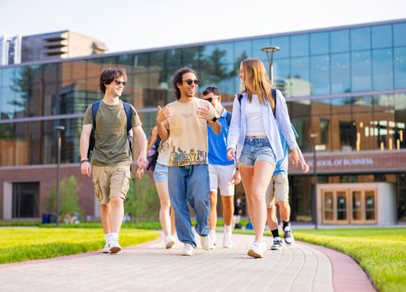 Six students walk and talk together across the South Quad on a sunny day