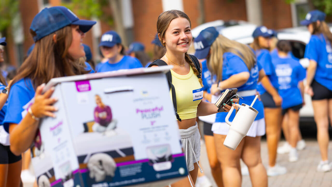 Students participating in move in crew carry boxes and push carts.