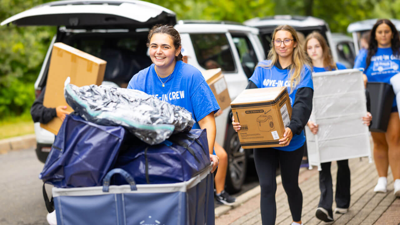 Students carry boxes and items.