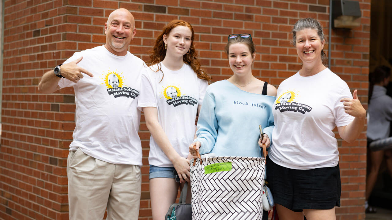 A first year student and their family smile for a photo.