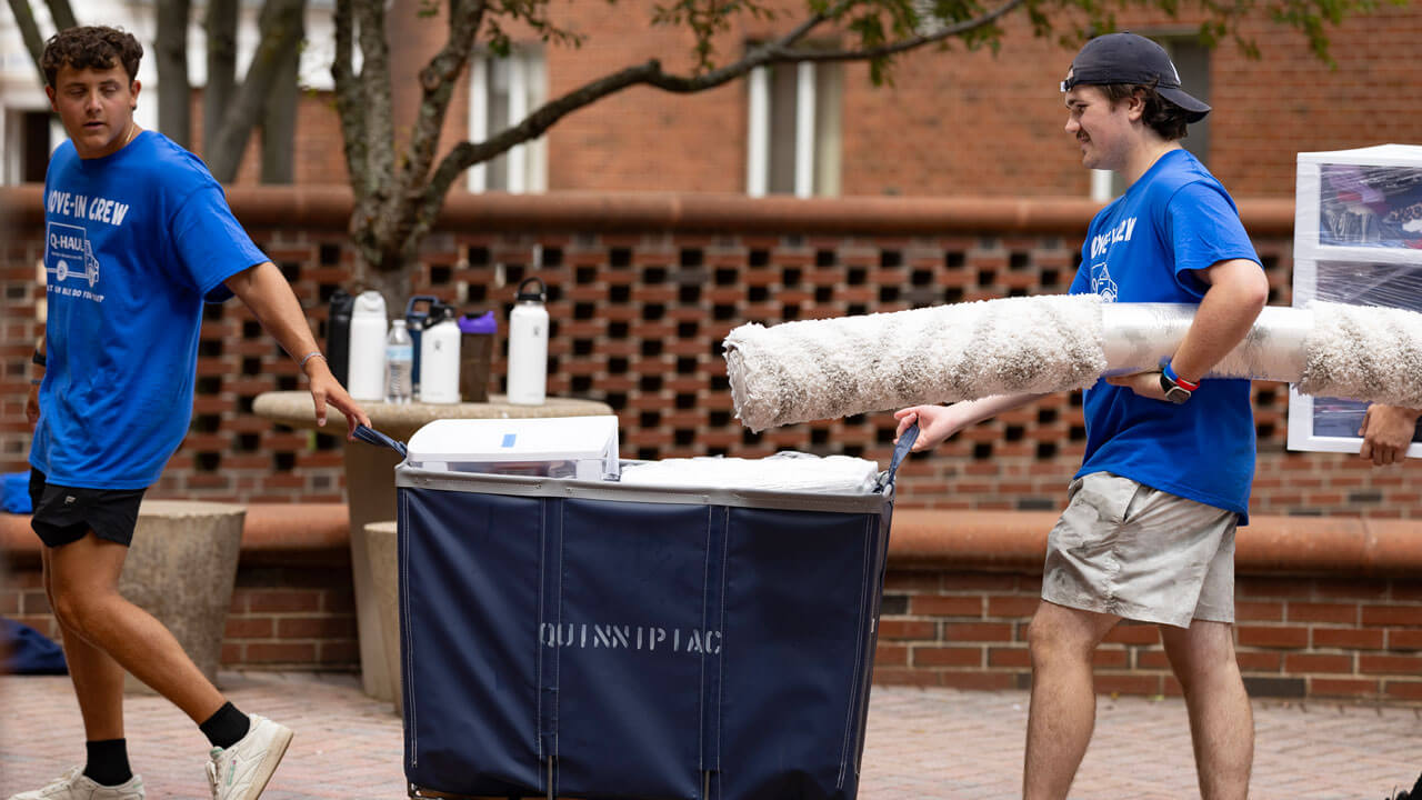 Students carry items into dorm buildings.