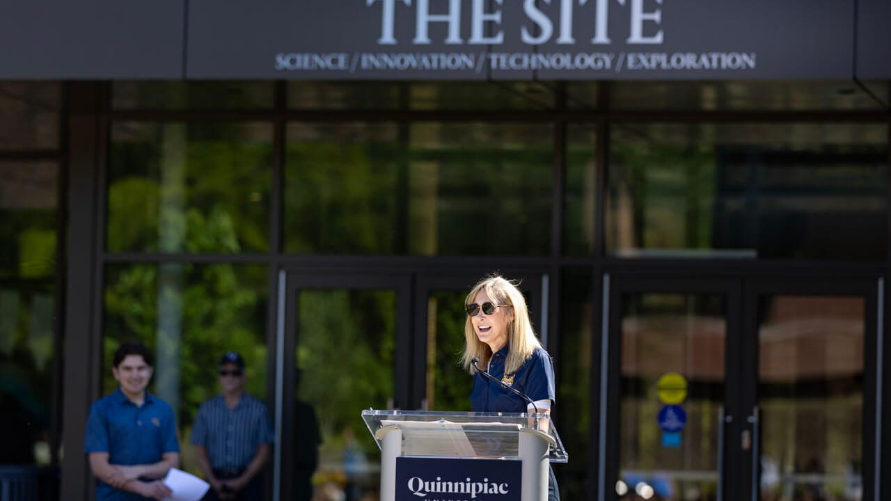 Marie Hardin speaks at a podium outside of The SITE building