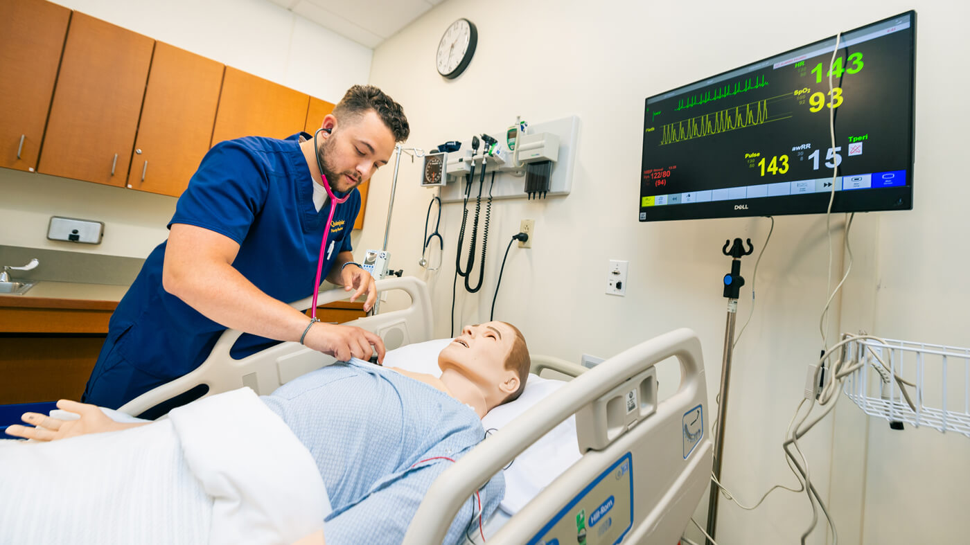 A nursing student listens to a manikin patients' heartbeat with a stethoscope in a North Haven campus simulation lab.