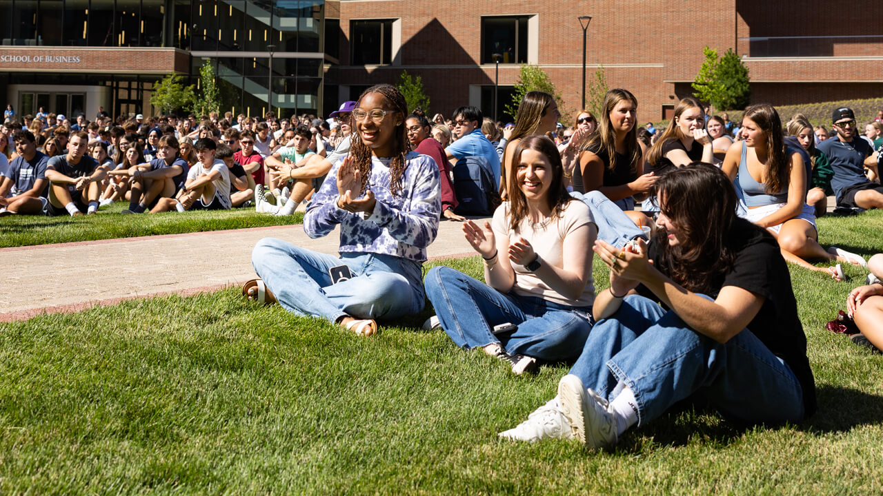 Dozens of new students talk and clap on the lawn of the South Quad during the welcome ceremony