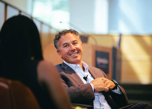 Chuck Sias smiling and talking to guest speaker 1