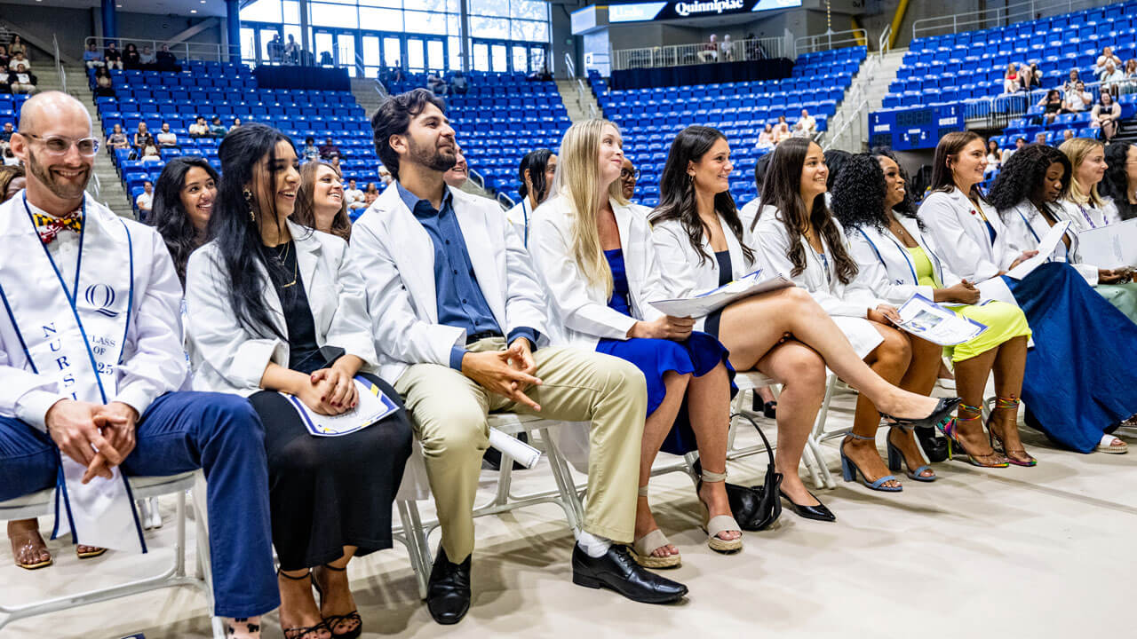 Nurses in their white coat sitting down looking up at the stage