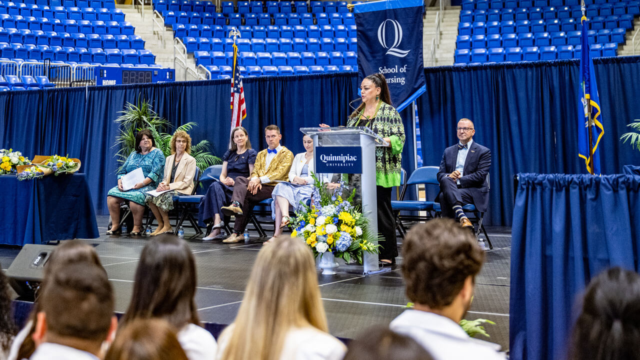 Speaker stands at a podium in the M&T Bank Arena at the 2025 pinning ceremony