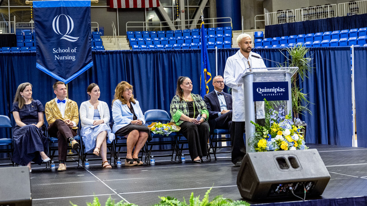 Speaker in a white coat presenting at the M&T Bank arena
