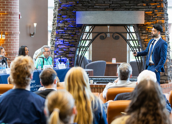 A man in a suit speaking to a panel of judges