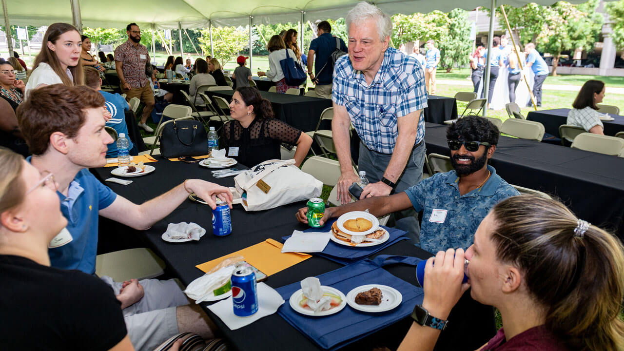Professors and students sitting at tables and talking