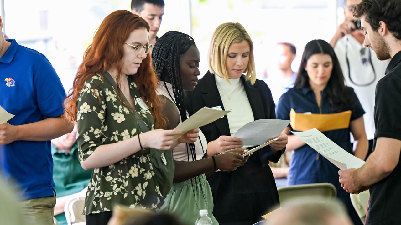 Students reading pamphlets underneath the tent