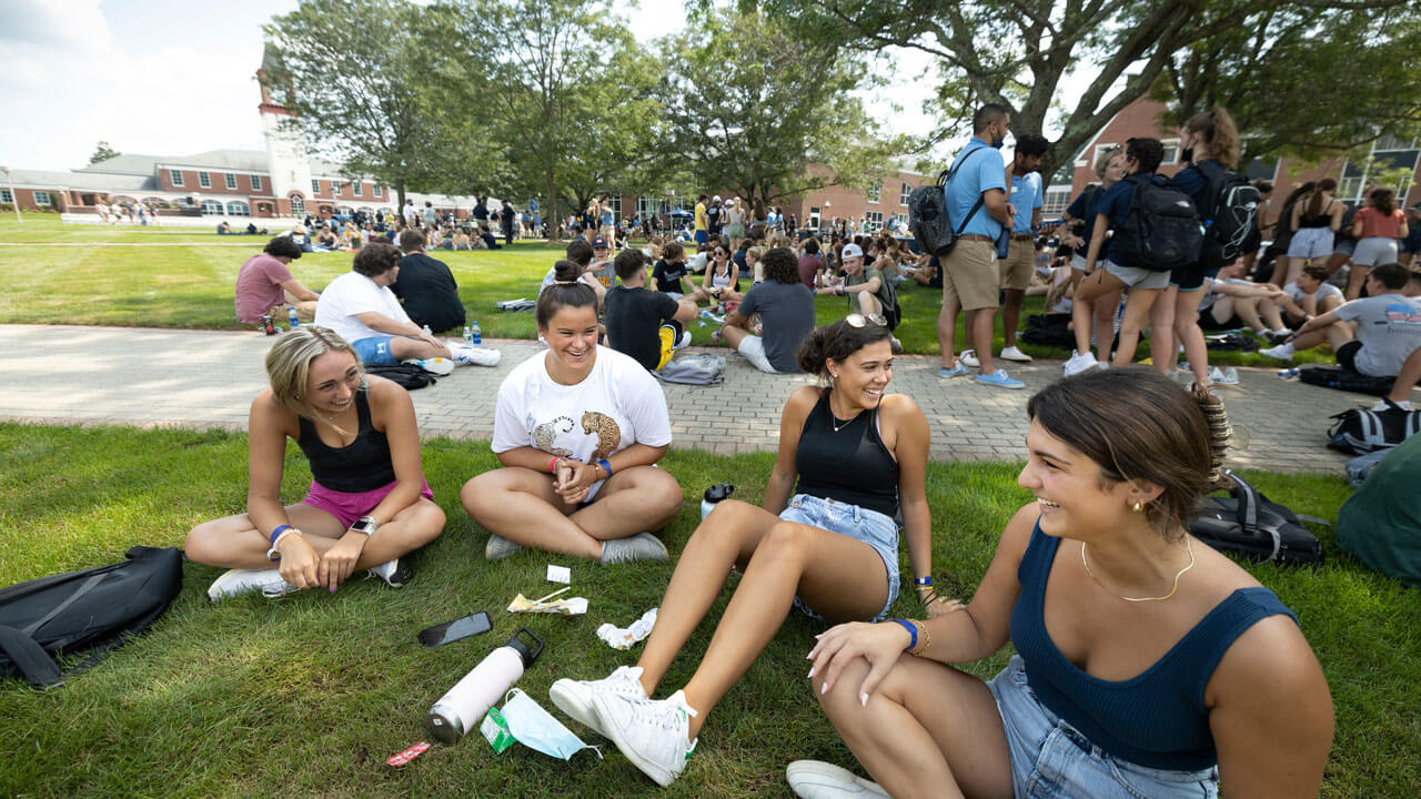 Students talk and laugh together as they sit on the grassy quad
