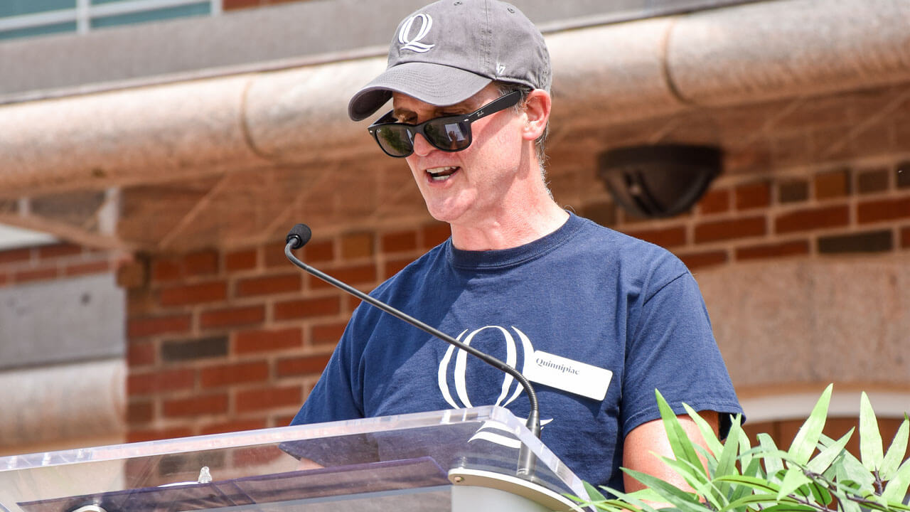 Tom Ellett speaks from the podium on the library steps during the Welcome ceremony