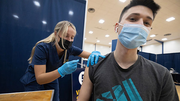 A student receives a vaccine from a medical professional