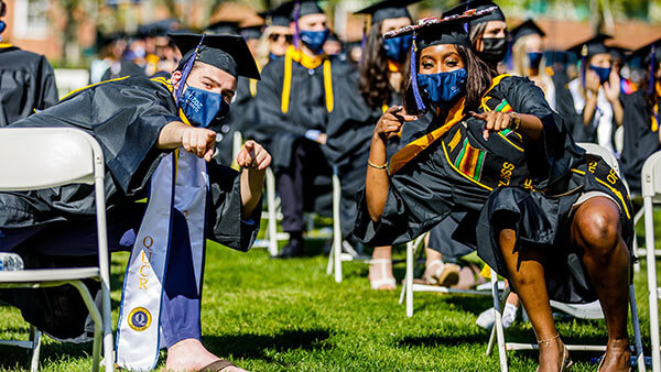 Two student celebrate their graduation at the 2020 commencement ceremony