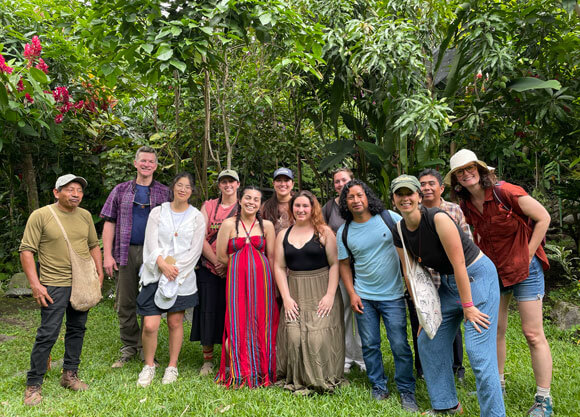 Faculty and students smile against a lush green background in Guatemala