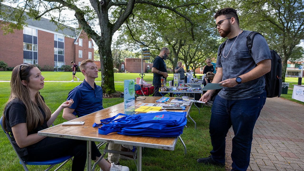 A student learns more about one of the local businesses on the Quad