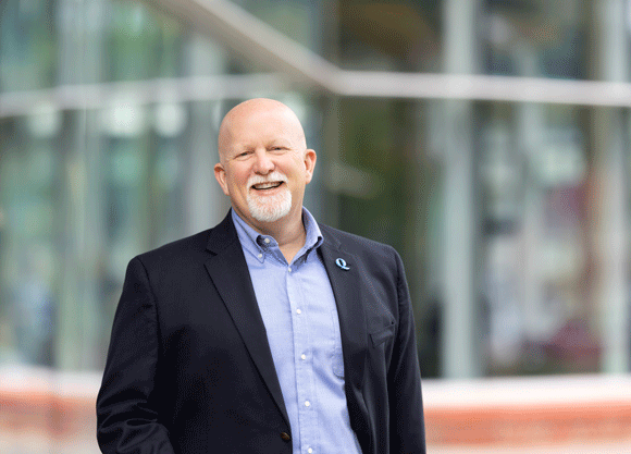 John Bau smiles against a blurred background