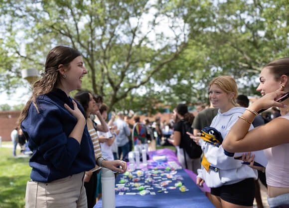 Students talk at a fair table outside on the quad