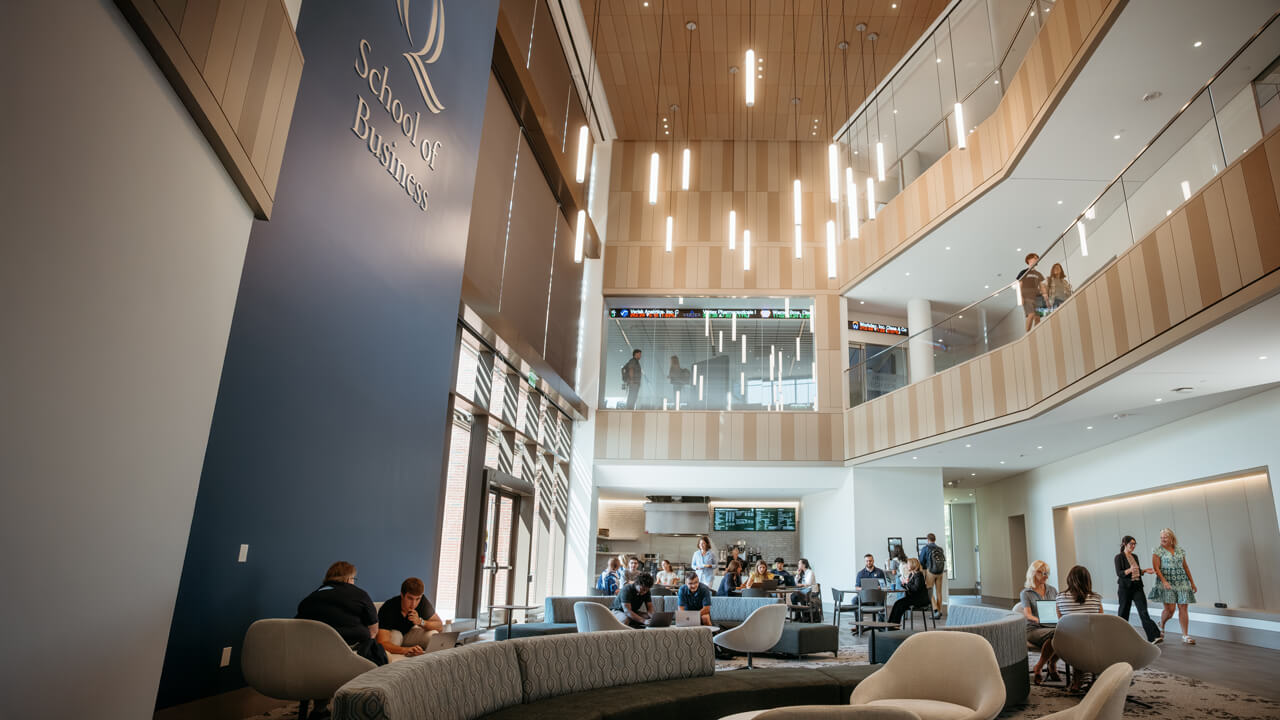 Interior of School of Business atrium with students and faculty socializing.