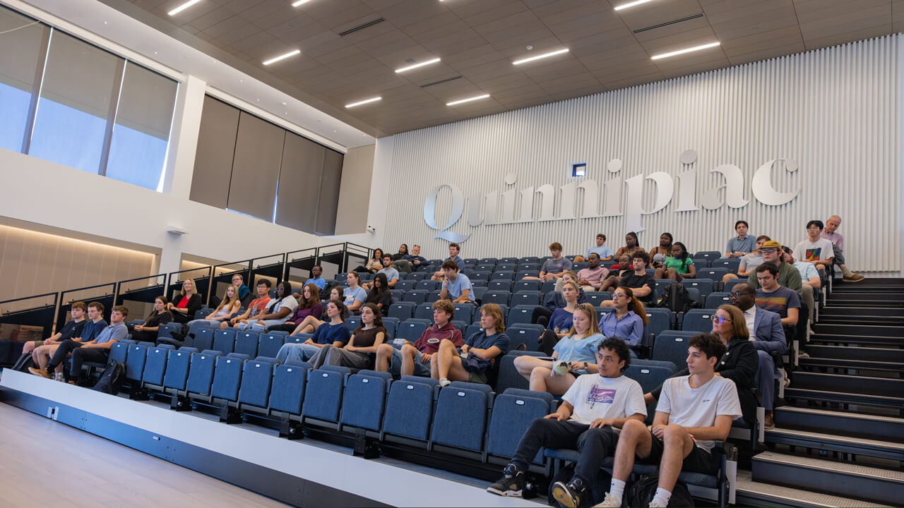 Students and faculty members sit in the School of Business event space.