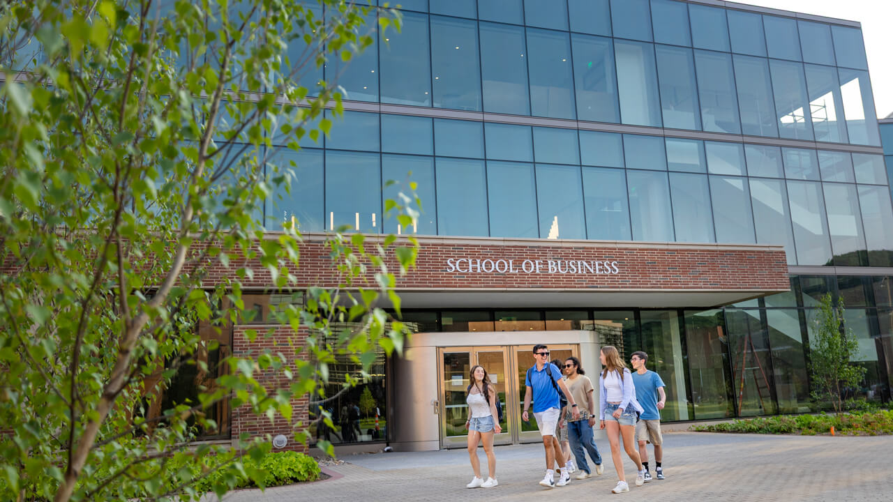 Quinnipiac students walk outside of the School of Business entrance on the South Quad.